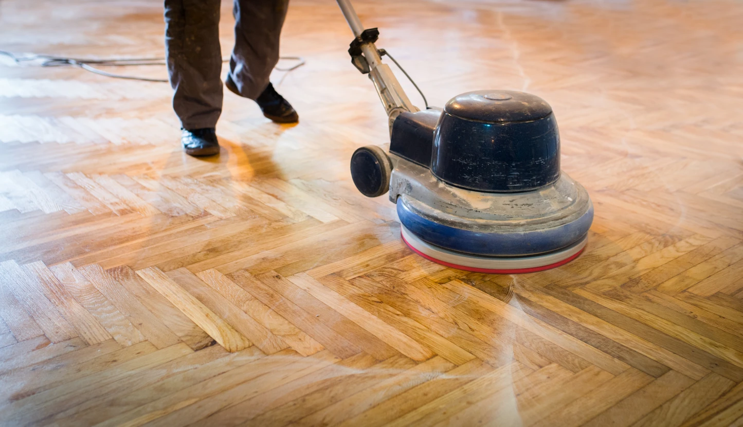 Intérieur professionnel avec ouvrier effectuant ponçage de parquet en bois massif